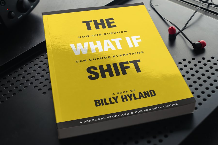 The What If Shift book with wireless earbuds, representing the audiobook